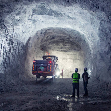 Two men standing in an underground mine looking at an underground drill rig